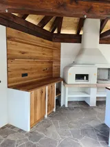 Zunanja kuhinja s kamnitim pultom in lesenimi omarami